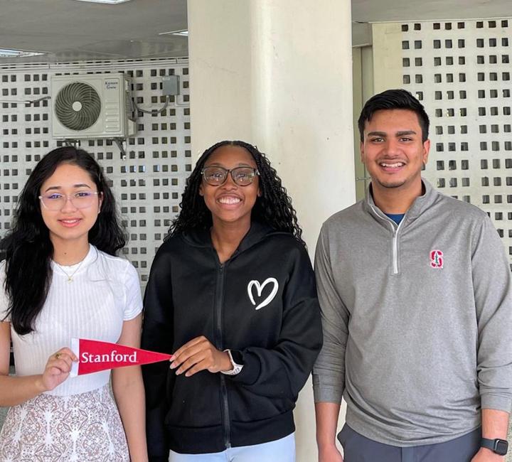 Three Next Step mentors smiling, holding a Stanford pennant